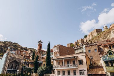 01.06.2019 Tiflis, Gürcistan: Turistlerin yürüdüğü eski şehrin merkezinde güzel renkli çatıları olan eski taş evlerin manzarası