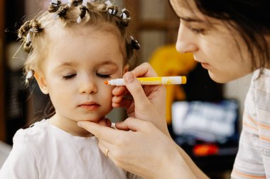 01.06.2019 Vinnitsa, Ukrayna: anne ve kızı, makyaj sanatçısı olarak bir çocuğun yüzüne çil çizer. Mutlu bir ailede ev oyunları ve eğlence.