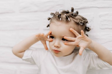 01.06.2019 Vinnitsa, Ukrayna: Parlak samimi bebek duygularına sahip bir kızın portresi. Küçük kıvırcık kız fotoğraf için poz veriyor.