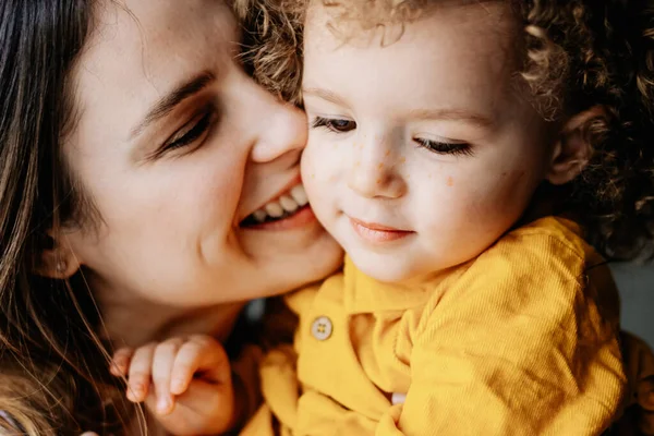 01.06.2019 Vinnitsa, Ukrayna: anne ve kızı. Çekici genç anne ve kırılgan kıvırcık kızı evde sarılıp eğleniyorlar.