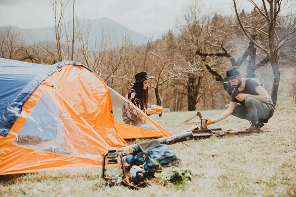 スタイリッシュな若い旅行者のカップル 山の中を歩く家族はテントを張り 朝食を準備し さらに旅程を計画する — ストック写真