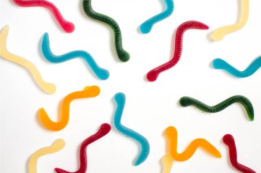 jelly fruit candies of different colors in the form of worms on a white paper background. Imitation of crawling candy on paper clipart