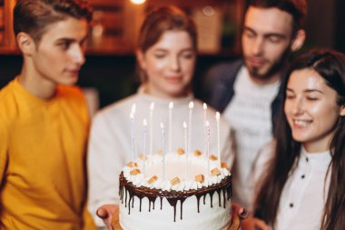 Çekici kız pastadaki mumları söndürür ve doğum gününde onu kutlamaya gelen en iyi arkadaşlarının yanında dilek tutar.