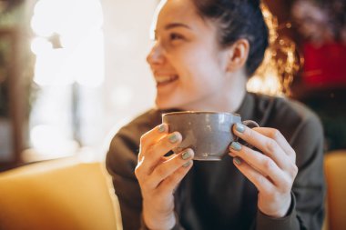 Pencerenin yanındaki kafede kahve içen genç ve tatlı bir kız.