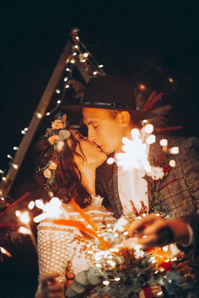 夜に結婚式のアーチの前に若い花嫁のカップルの肖像画 本質的にロマンチックな結婚式 電気の庭の照明は結婚式のパーティーを照らす — ストック写真