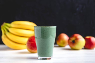 Sağlıklı bir işletme için meyve kokteylinin tanıtım çekimi. Fotoğrafta, meyve ve alg spirulinasından yapılmış yeşil bir içecek bardağı var.