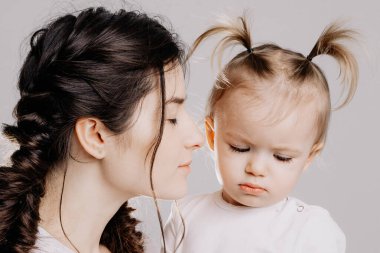 Mutlu anne ve kız stüdyoda beyaz bir arka planda çekim yapıyorlar.