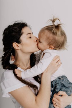Mutlu anne ve kız stüdyoda beyaz bir arka planda çekim yapıyorlar.