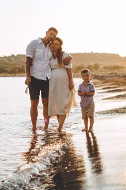 Şık bir adam, karısı ve küçük oğulları gün batımında deniz kenarında dinleniyorlar. Gerçek bir aile albümünden fotoğraf, deniz kenarında geçirdikleri bir tatilin anıları.