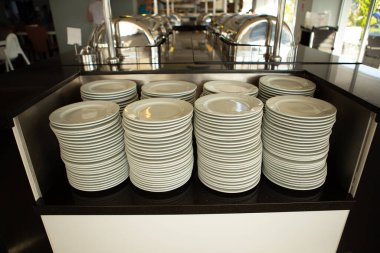Otel restoranındaki açık büfede konukların gelmesini bekleyen bir sürü temiz tabak var.