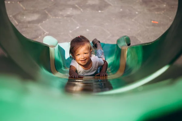 little smiling girl goes down from the big slide, photo from above