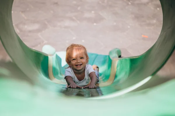 little smiling girl goes down from the big slide, photo from above