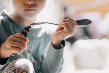 25.06.2018 Vinnitsa, Ukrane: küçük kız pencere kenarında duran kemik ve palet bıçağıyla tuvale yağlı boya çiziyor.