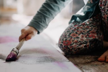 25.06.2018 Vinnitsa, Ukrane: küçük kız pencere kenarında duran kemik ve palet bıçağıyla tuvale yağlı boya çiziyor.