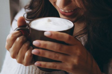 05.02.2020 Vinnitsa, Ukrayna: büyük pembe kahve fincanı olan güzel bir kız en sevdiği kafede bir sandalyeye oturur ve günlük kahvesini içer ve bir kız arkadaşıyla konuşur.