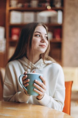 07.03.2020 Odessa, Ukrayna: rahat bir kafede kahve içen çekici genç kız, baharın başında, gülümser ve hayattan zevk alır.