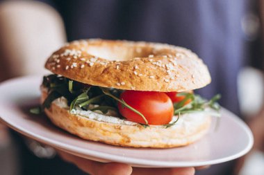 Garsonun eli lezzetli ve sulu bir simit tutuyor.