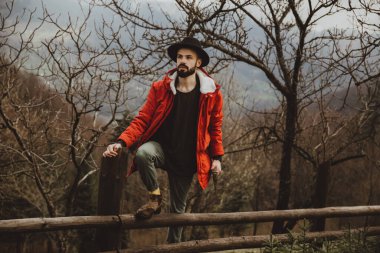 Sakallı hippi, şapkalı ve ceketli adam piknik için odun kesiyor ve hazırlıyor.