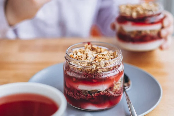jar dessert: granola with dried fruits and cherry jam, modern dessert in natural ingredients in a cozy cafe