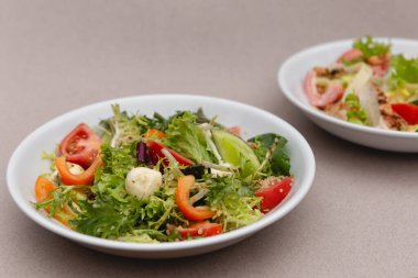 Çekici bir arkaplana yerleştirilmiş sosla karıştırılmış taze salata içerikli beyaz tabaklar. Menü, pankart veya reklam için bir yer