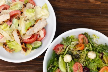 Çekici bir arkaplana yerleştirilmiş sosla karıştırılmış taze salata içerikli beyaz tabaklar. Menü, pankart veya reklam için bir yer