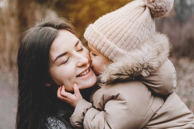 Parkta serin bir sonbahar gününde yürüyen güzel anne ve küçük kızının portresi.