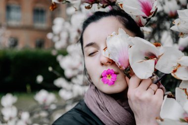 Genç kız Ukrayna 'daki Chernivtsi Üniversitesi' nde beyaz ve pembe manolya çiçeklerinin çiçeklenmesinin tadını çıkarıyor.