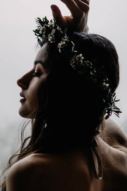 Güzel makyajlı şık bir gelinin portresi, kafasında bir çelenk ve zarif minimalist bir elbise.