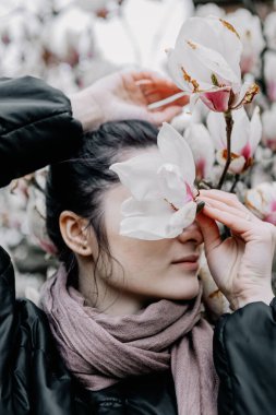 Genç kız Ukrayna 'daki Chernivtsi Üniversitesi' nde beyaz ve pembe manolya çiçeklerinin çiçeklenmesinin tadını çıkarıyor.