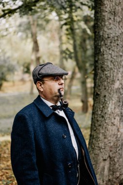 13.10.2019 Vinnitsa, Ukrayna: gözlük takan şık bir adamın portresi tütünlü bir pipo ve orijinal 1945 model bir şapka