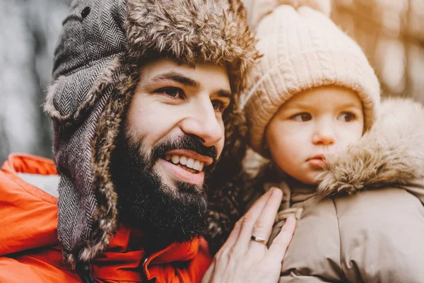 Handsome bearded young dad and his little sweet daughter have fun outdoors in winter.  Family concept.