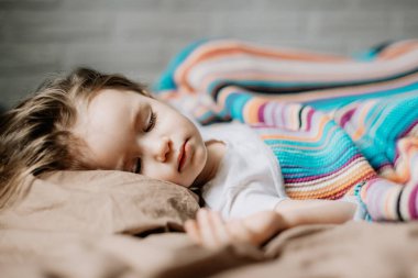 01.06.2019 Vinnytsia, Ukrayna: İki yıllık genç anne ve bebek sarılarak yatıyor, çocuklar için gündüz uykusu kavramı. Annem bebeğini uyuturken uyuyakalmış.