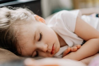 01.06.2019 Vinnytsia, Ukrayna: İki yıllık genç anne ve bebek sarılarak yatıyor, çocuklar için gündüz uykusu kavramı. Annem bebeğini uyuturken uyuyakalmış.