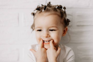 01.06.2019 Vinnytsia, Ukrayna: Çocuk oyunculuğu, otantik küçük kız beyaz bir duvarın önünde farklı duygular gösteriyor