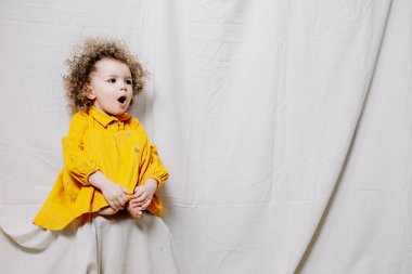 01.06.2019 Vinnytsia, Ukrayna: Parlak samimi bebek duygularına sahip bir kızın portresi. Küçük kıvırcık kız fotoğraf için poz veriyor.