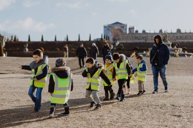 13: 02: 2020 Paris, Fransa: ilkokul çocukları Versailles 'deki bir bahçe turu için parlak sarı jöleler giyip el ele tutuşuyorlar.