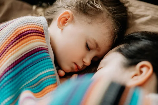 01.06.2019 Vinnytsia, Ukrayna: İki yıllık genç anne ve bebek sarılarak yatıyor, çocuklar için gündüz uykusu kavramı. Annem bebeğini uyuturken uyuyakalmış.