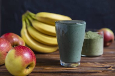 Bardakta pipetle kibrit tozu bulunan taze yeşil meyve püresi. Katı arkaplan, kopyalama alanı