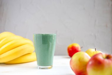 Sağlıklı bir işletme için meyve kokteylinin tanıtım çekimi. Fotoğrafta, meyve ve alg spirulinasından yapılmış yeşil bir içecek bardağı var.