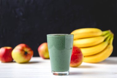 Sağlıklı bir işletme için meyve kokteylinin tanıtım çekimi. Fotoğrafta, meyve ve alg spirulinasından yapılmış yeşil bir içecek bardağı var.