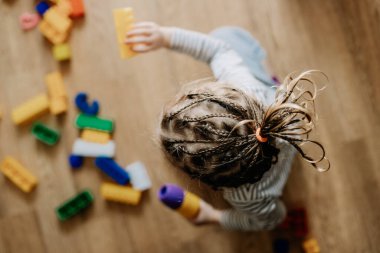 01.02.2019 Vinnitsa, Ukrayna: Ebeveynler meşgulken evde tek başına oynayan şirin saç stili olan küçük bir kızın portresi