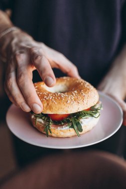 Garsonun eli lezzetli ve sulu bir simit tutuyor.
