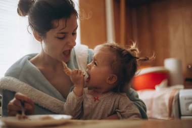 seçici odaklanma, gürültü etkisi: güzel bir kız çocuğu, annesiyle birlikte sabah mutfakta kahvaltı yapıyor.