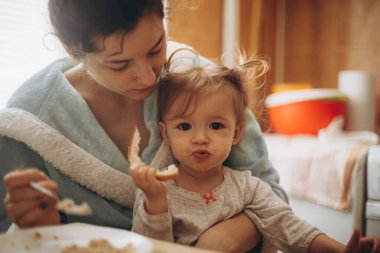 seçici odaklanma, gürültü etkisi: güzel bir kız çocuğu, annesiyle birlikte sabah mutfakta kahvaltı yapıyor.