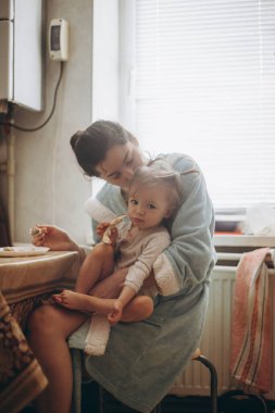 seçici odaklanma, gürültü etkisi: güzel bir kız çocuğu, annesiyle birlikte sabah mutfakta kahvaltı yapıyor.
