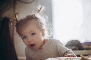 seçici odaklanma, gürültü etkisi: güzel bir kız çocuğu, annesiyle birlikte sabah mutfakta kahvaltı yapıyor.