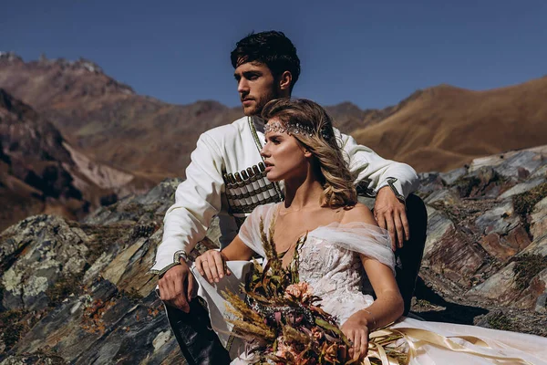 young, stylish, loving brides posing for a photo on an incredibly beautiful background of the Caucasus Mountains: hugging, kissing, laughing, and rejoicing in the happiest day of their lives