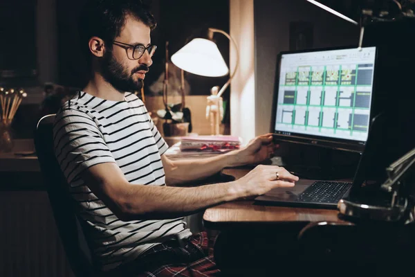 Stylish bearded man works at night at the computer at home during quarantine in self-isolation