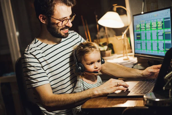 Stylish Bearded father working at home while babysitting his playful daughter