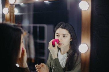 Lüks güzellik salonunda büyük aynaları ve aydınlığı olan şık bir kız makyaj yapıyor.